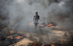 A young protester runs away from tear gas thrown by Israeli soldiers in Gaza.