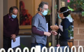 People wearing face masks are seen at the entrance of the Menarock Life aged care facility, where a cluster of infections has been reported.  There are Covid-19 cases linked to 40 aged care facilities in Victoria.