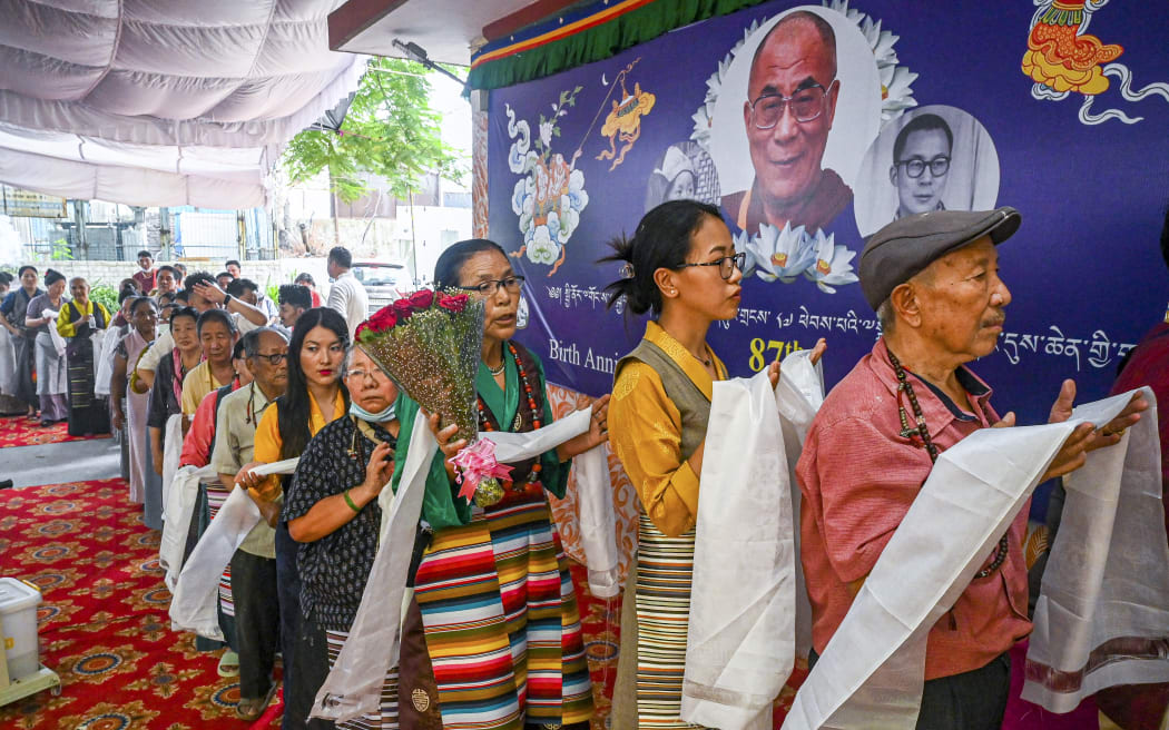 Exiled Tibetans wait in a queue to place offerings to mark the 87th birthday of their spiritual leader, the Dalai Lama, in New Delhi on July 6, 2022. (Photo by Prakash SINGH / AFP)