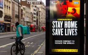 A delivery man on his bicycle is seen riding by the NHS 'Stay Home' poster as the UK's government introduced strict Coronavirus restrictions earlier this month due to sharp increase in numbers of Covid-19 cases in UK o)