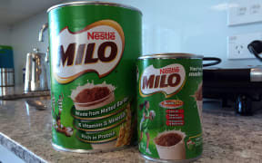 A tin of 'old' Milo, next to a smaller tin of 'new' Milo.