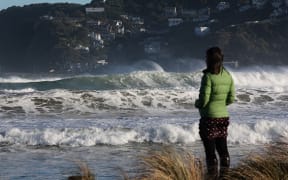 A passer-by watches high waves roll in during a storm surge at Lyall Bay on Wellington's South Coast.