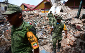 Police and army members search through rubble in Juchitan