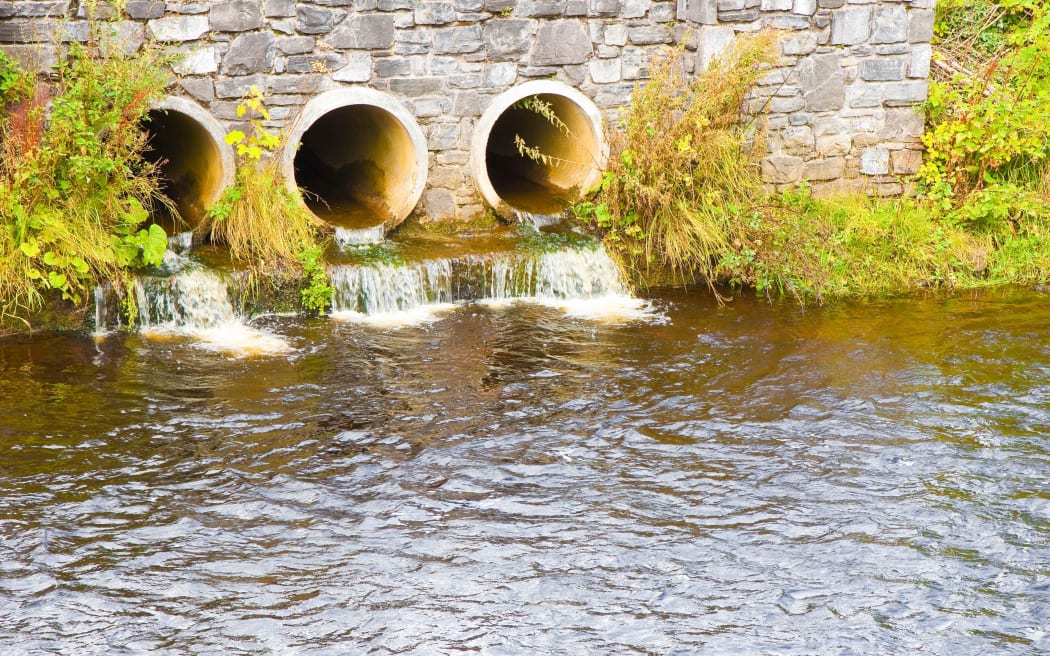 Toxic water running in concrete drainpipe towards the river
