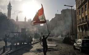 A Lebanese protester waves the national flag during clashes with security forces in downtown Beirut on August 8, 2020,