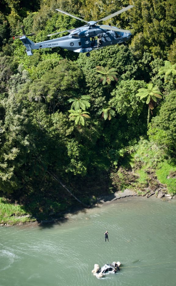 An NH90 helicopter winches the car from the Mohaka River.