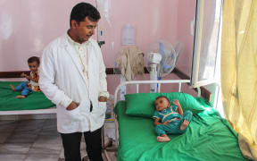 A hospital staffer looks at a Yemeni child suffering from malnutrition lying on a bed at a hospital in the northern district of Abs in the northwestern Hajjah province on September 19, 2018.