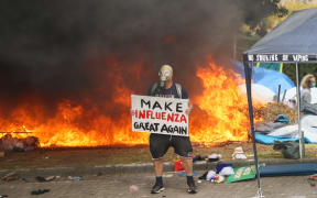 Make influenza great again protester with gas mask in front of fire