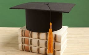 A mortarboard sitting on top of a stack of books