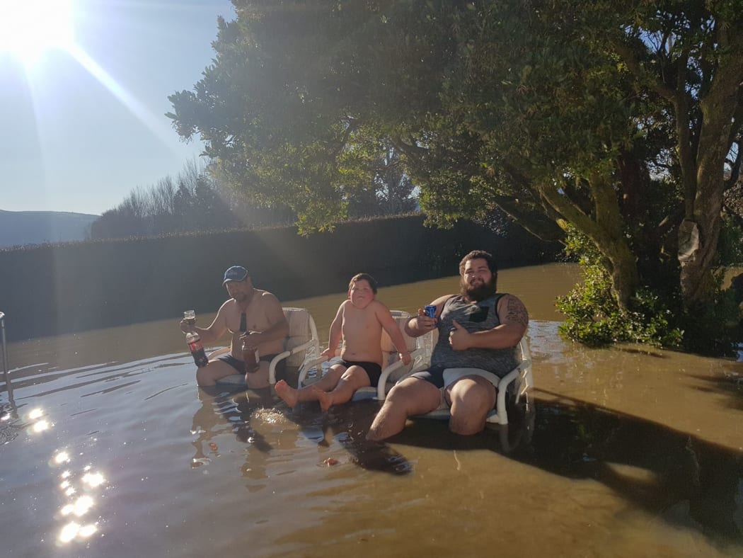 A group of locals relaxes in a flooded backyard along the Taieri Gorge Railway.