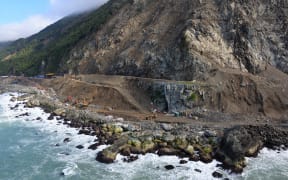 Aerial shot of huge cliff with workers cut back debris