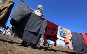 A displaced Iraqi woman, who fled her home due to attacks by IS, hangs up her washing at a refugee camp near Arbil.