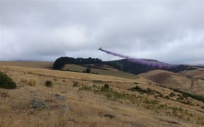 A plane dropping fire retardant over the Port Hills.
