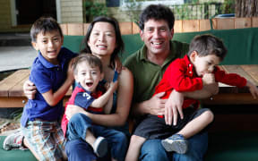 Mike Lanza at his front yard picnic table, surrounded by his family: from left, Marco (7), Leo (2), wife Perla Ni, and Nico (4).