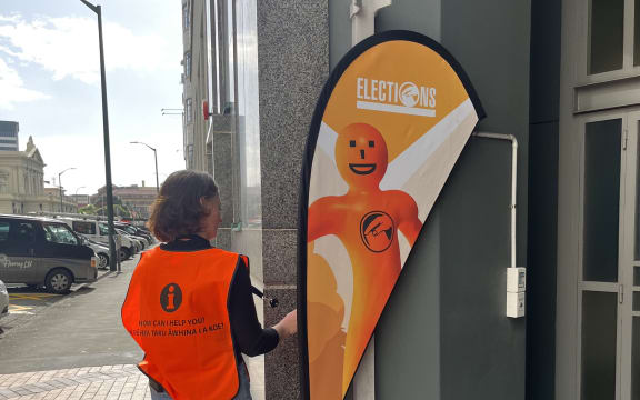 An Electoral Commission worker adjusts a voting sign at a polling station in Stout Street, central Wellington