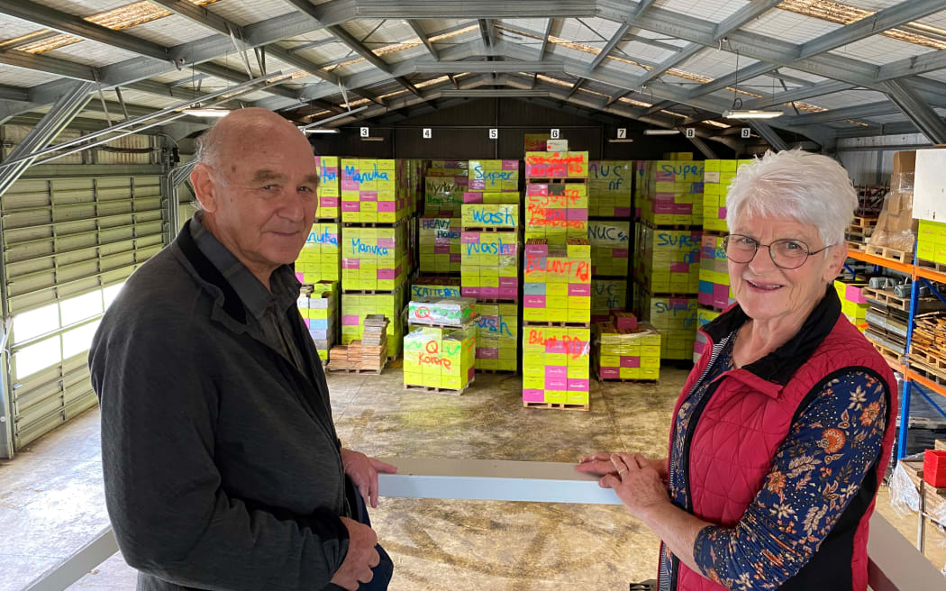 Bill (left) and Margaret Bennett (right) stand at the top of their bee house with empty hives stacked high ready to go for summer.