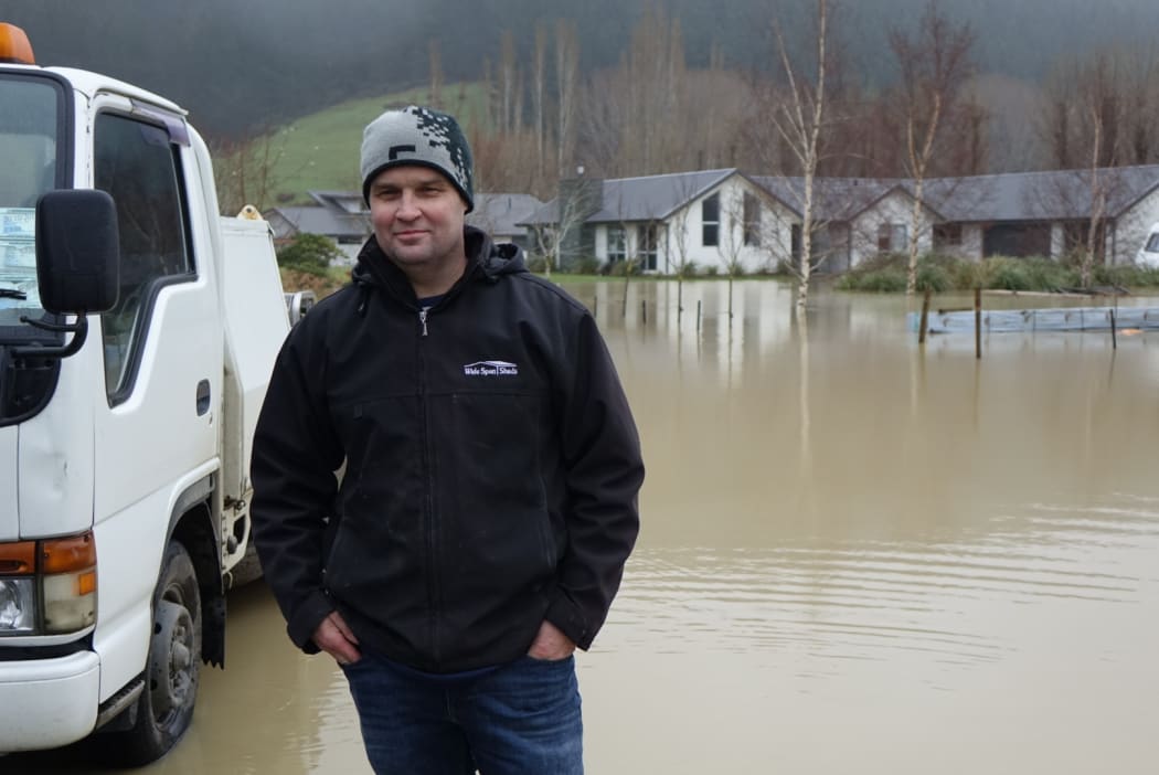 Craig Miller stands next to the flooding at a Dunedin subdivision.