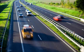 A file photo shows blurred cars on a four-lane highway.