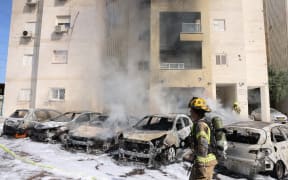 Israeli fire brigade teams douse the blaze in a parking lot outside a residential building following a rocket attack from the Gaza Strip in the southern Israeli city of Ashkelon, on October 7, 2023. Palestinian militants have begun a "war" against Israel, the country's defence miniser said on October 7 after a barrage of rockets were fired and fighters from the Palestinian enclave infiltrated Israel, a major escalation in the Israeli-Palestinian conflict. (Photo by AHMAD GHARABLI / AFP)