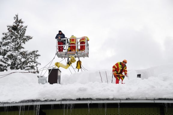 11 January 2019, Bavaria, Inzell: Firefighters clear the snow from the roof of a house. AFP