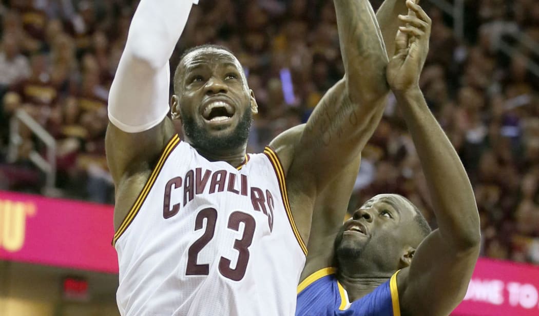 LeBron James, left, drives to the basket over Draymond Green