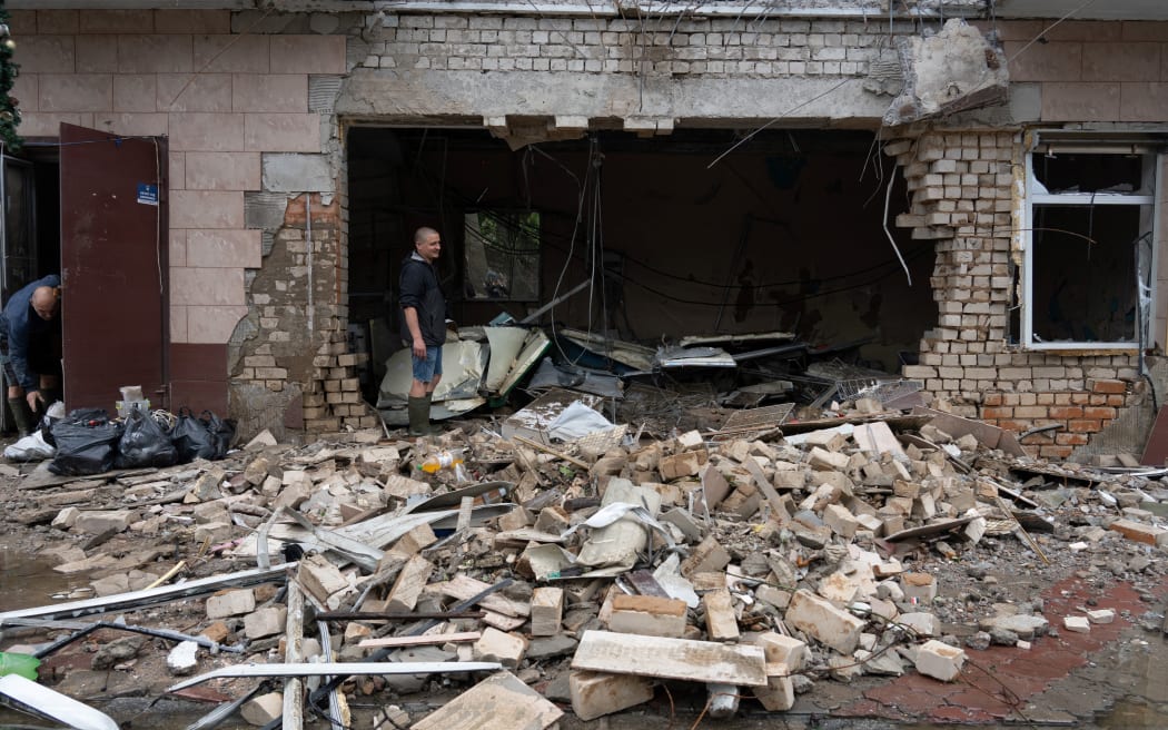 Locals clear debris from shops destroyed by Russian artillery fire in Kherson on June 12, 2023, as the area deals with massive flooding from the destruction of the Kakhovka hydroelectric dam.  (Photo credit: Oleksii FILIPPOV/AFP)