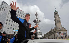 Peter Burling waves to the crowd at the America's Cup parade in central Auckland.