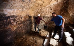 An Israeli antiquity authority worker digs at an excavation site where a 2000-year old Jewish ritual bath, called a "Mikveh", was discovered in a cave.
