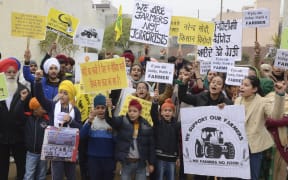 Students along with their parents hold placards and shout slogans in support of farmers protesting against the central government's recent agricultural reforms, in Amritsar.