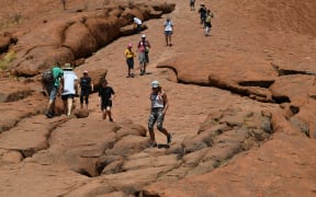 Tourists climb the Uluru, also known as Ayers Rock, on a sunny day at Uluru-Kata Tjuta National Park in Australia's Northern Territory on October 25, 2019. -