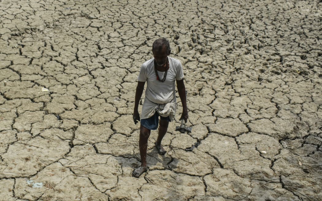 Un homme marche le long d'un lit de rivière semi-aride par une chaude journée d'été à la périphérie de Kolkata, en Inde, le 14 mai 2023.