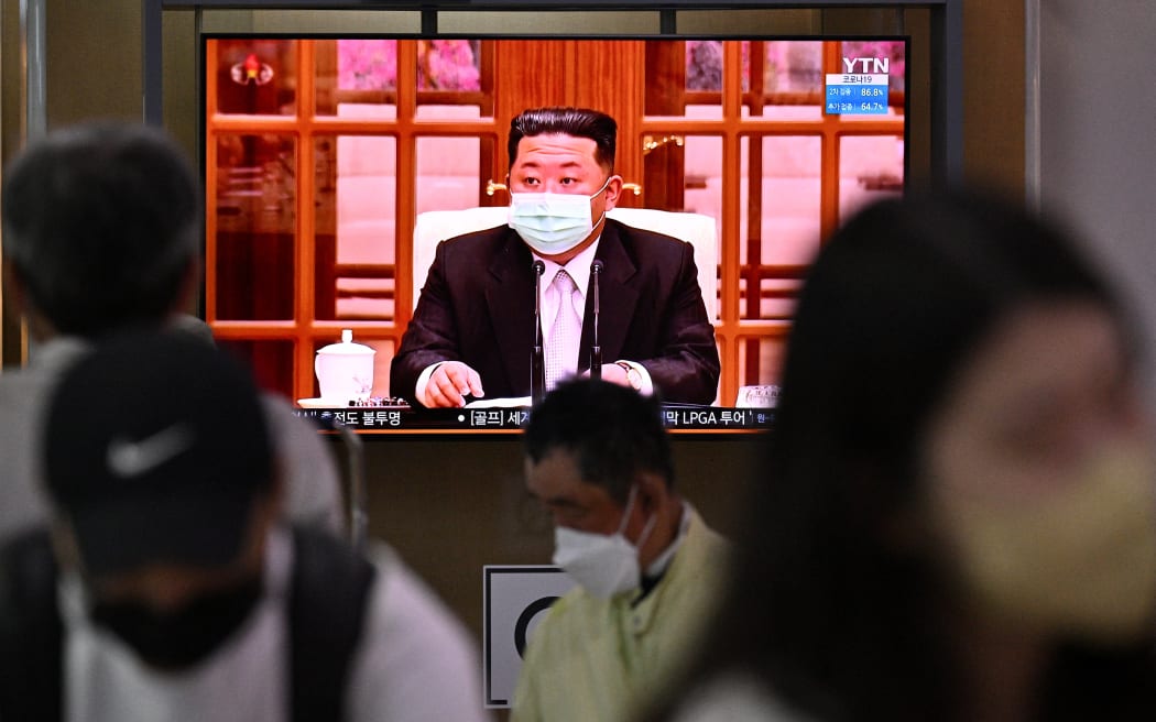 People sit near a screen showing a news broadcast at a train station in Seoul on May 12, 2022, of North Korea’s leader Kim Jong Un appearing in a face mask on television for the first time to order nationwide lockdowns after the North confirmed its first-ever Covid-19 cases.