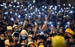 Protesters hold up their mobile phones as they gather outside the police headquarters in Hong Kong on June 21, 2019.