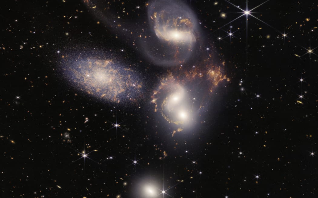 This image released by NASA on July 12, 2022, shows Stephan’s Quintet captured by the James Webb Space Telescope (JWST), a visual grouping of five galaxies, in a new light. This enormous mosaic is JWST’s largest image to date, covering about one-fifth of the Moon’s diameter. It contains over 150 million pixels and is constructed from almost 1,000 separate image files. - The JWST is the most powerful telescope launched into space and it reached its final orbit around the sun, approximately 930,000 miles from Earths orbit, in January, 2022. The technological improvements of the JWST and distance from the sun will allow scientists to see much deeper into our universe with greater detail. (Photo by Handout / NASA / AFP) / RESTRICTED TO EDITORIAL USE - MANDATORY CREDIT 