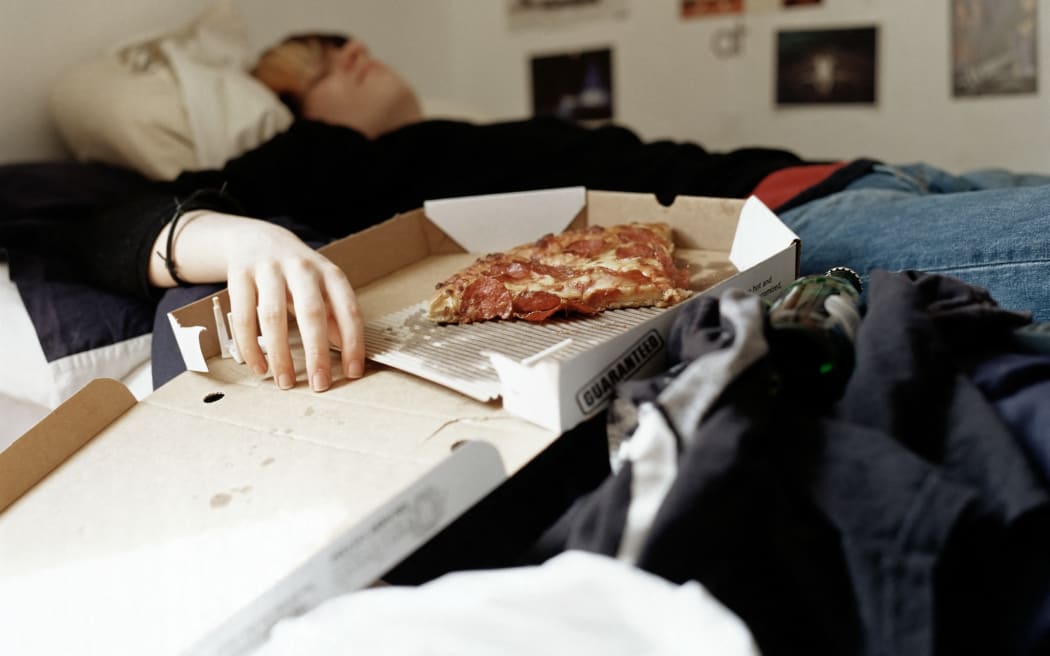 Un garçon dort avec une pizza sur le lit (Photo par Alice Tomlinson/Crédit image/Crédit image via AFP)