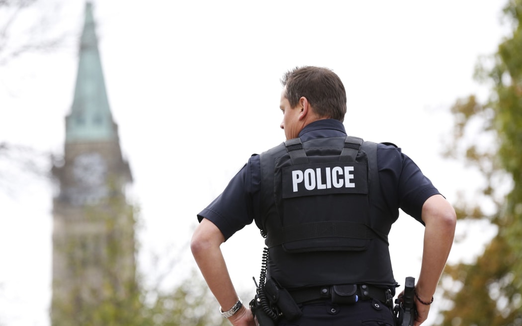 A police officer stands guard with the Peace Tower in the background following shootings in downtown Ottawa.