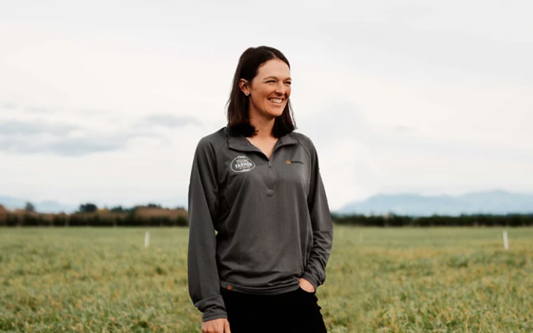 Emma Poole stands in a paddock smiling and looking off camera.