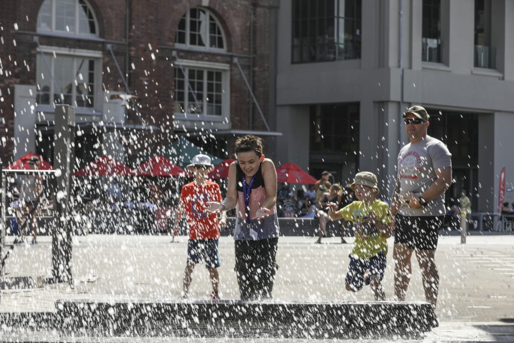 Summer in Wellington, a boy is splashed by the people jumping into the harbour.