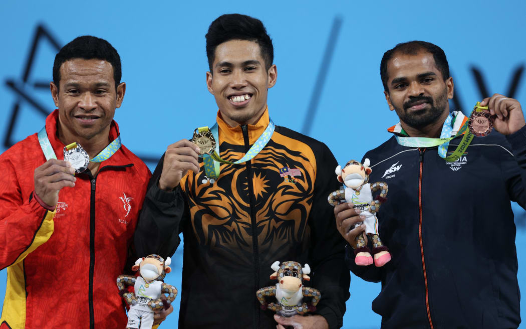 Gold medallist Malaysia's Aznil Bin Bidin Muhamad (C), silver medallist Papua New Guinea's Morea Baru and bronze medallist India's Gururaja Gururaja pose during the medal presentation ceremony for the mens 65kg weightlifting event on day two of the Commonwealth Games at the NEC Arena in Birmingham, central England, on July 30, 2022. (Photo by Darren Staples / AFP)