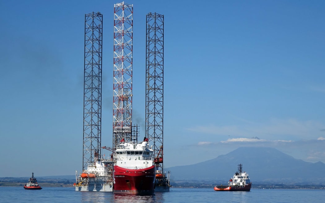 Boat and oil rig in clam sea and mountain behind