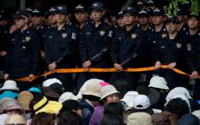 Followers sit before police outside the compound of church leader Yoo Byung-Eun on Wednesday.