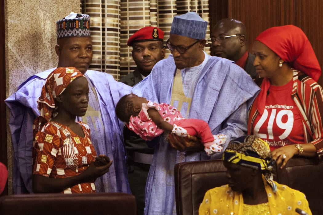 Nigerian President Mohammadu Buhari holds the daughter of Amina Ali Nkeki.