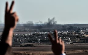 Kurdish onlookers react as they watch smoke billowing from Kobane, which has been under attack by Islamic State.