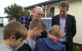 Russel Norman and Laingholm Primary School students looking at solar equipment.