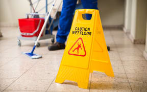 Worker Mopping Floor With Wet Floor Caution Sign On Floor