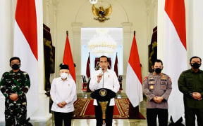 President Joko Widodo, flanked by his vice president and top military figures, announces the killing of the top intelligence official in Papua.