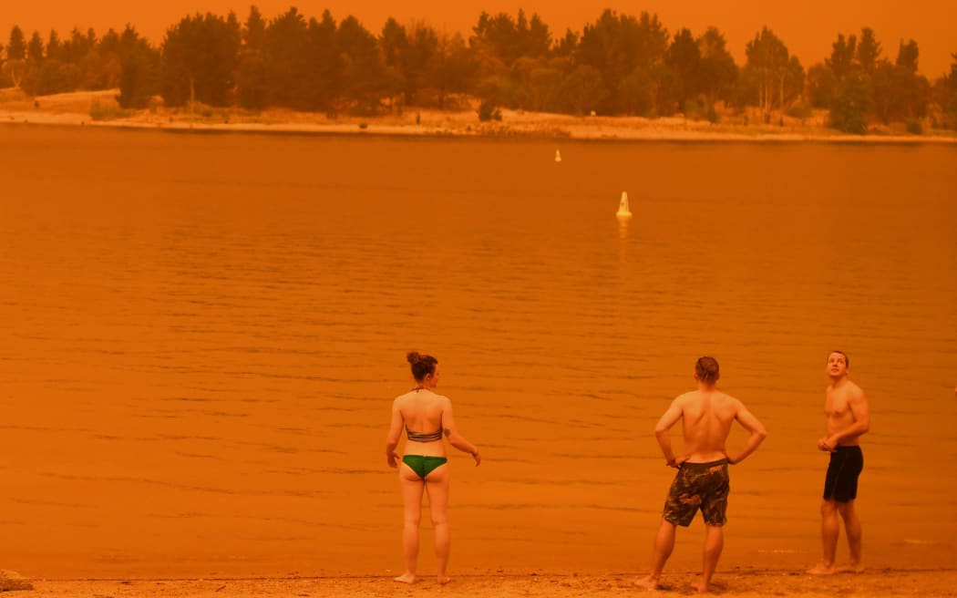 Residents take a dip to cool down at Lake Jindabyne, under a red sky due to smoke from bushfires, in the town of Jindabyne in New South Wales on January 4, 2020. -