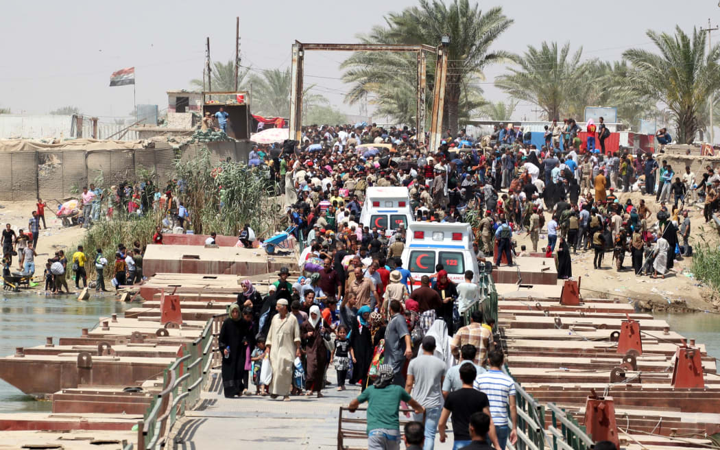 Residents of Ramadi who fled after the fall of the Iraqi city on Sunday cross a bridge on the outskirts of Baghad.