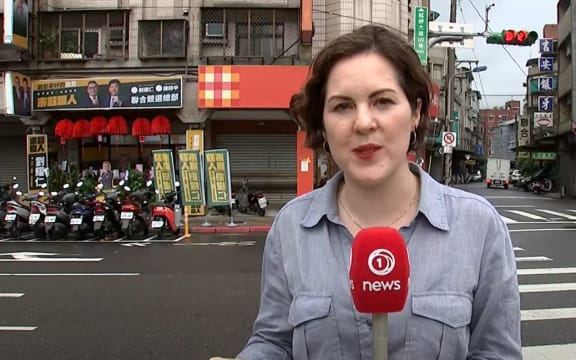 Cushla Norman en Taipei con anuncios de políticos pro-Taiwán sobre su hombro izquierdo, y pro-China en el derecho.