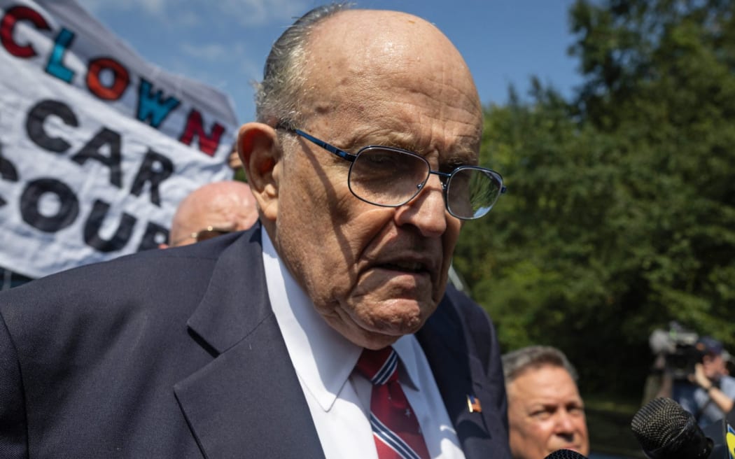 Rudy Giuliani frente a una pancarta que decía 'coche payaso'.